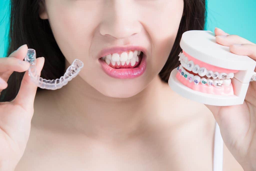 Patient holding invisalign aligners and traditional braces